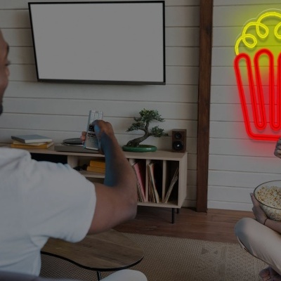 Sala de estar com homem e mulher, luz de néon de pipocas e televisão na parede