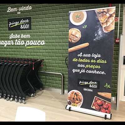 Interior de supermercado com carrinhos de compras e banner promocional em português