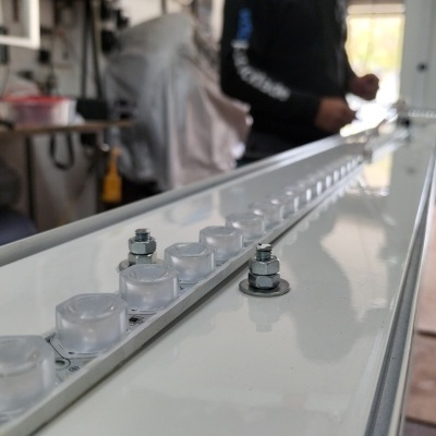 Estrutura metálica branca com parafusos e tampas transparentes numa oficina