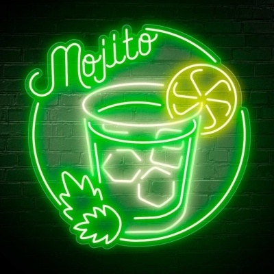 Letreiro de neon com a palavra 'Mojito' em verde, copo com gelo, rodela de limão e folhas em neon à frente de uma parede de tijolos preta.