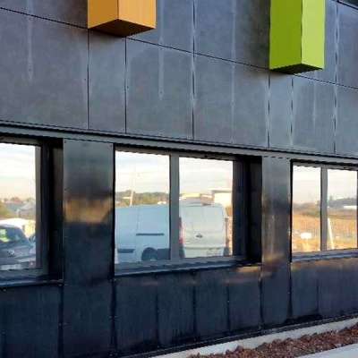 Edifício preto com janelas refletivas e painéis amarelo e verde