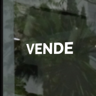 Vidro com a palavra VENDE e reflexo de planta e escada