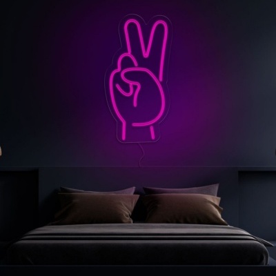 Luz neon rosa em forma de mão fazendo sinal de paz na parede acima da cama