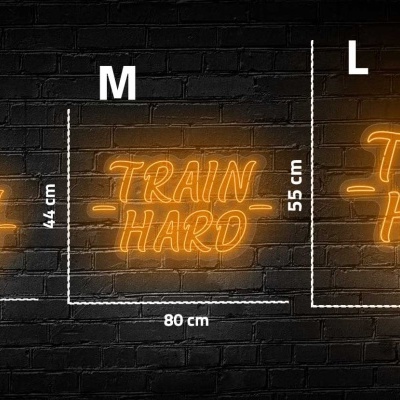 Três letreiros de neon laranja com texto 'TRAIN HARD' em parede de tijolos escuros em tamanhos S, M e L