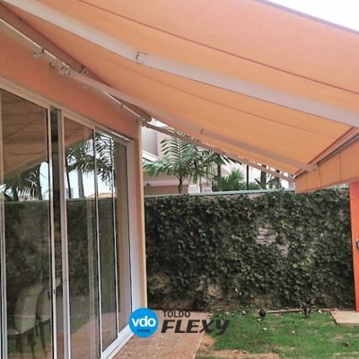 toldo laranja numa área de jardim com parede de vidro e relva