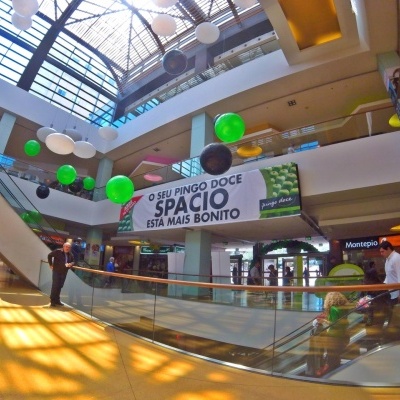 Centro comercial com banner branco e bolas decorativas suspensas.