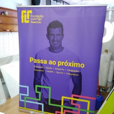 Banner roxo da Fundação Luis Figo com homem sorridente e texto amarelo
