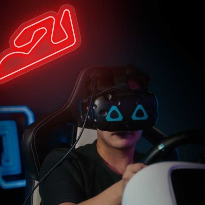 Pessoa com headset VR preto e volante de jogo, fundo escuro com luz néon vermelha em forma de skate