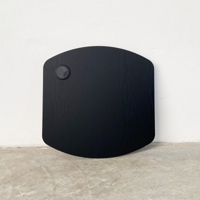 Tabuleiro de madeira preto com puxador redondo preto no chão junto a parede branca