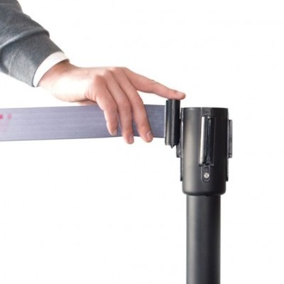 Mão a segurar uma faixa preta de tecido sobre um suporte de metal preto.