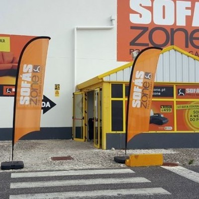 fachada de loja SOFÁS zone com bandeiras publicitárias laranja e anúncios visíveis