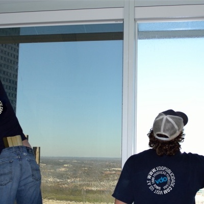 Dois homens a limpar janelas de vidro grandes em edifício alto