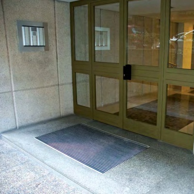 porta dupla de vidro com moldura metálica dourada e tapete metálico no chão