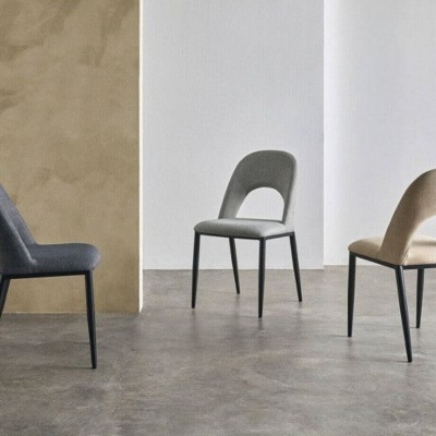 Três cadeiras estofadas em tecido cinzento e bege com pernas pretas, num chão e paredes neutras