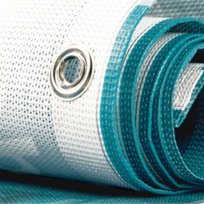 Tecido técnico branco com ilhó metálico enrolado sobre superfície azul-turquesa.
