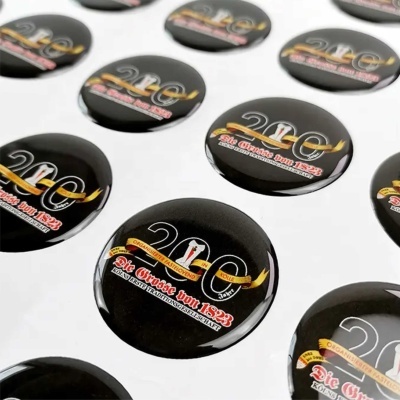 Chapas redondas pretas com texto e gráficos coloridos dispostas em superfície branca