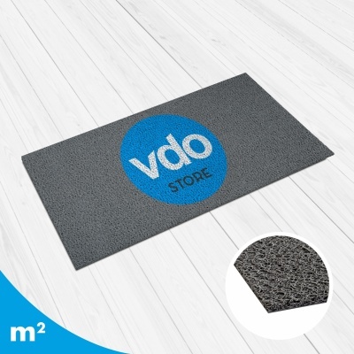 Tapete cinzento com círculo azul e texto 'vdo STORE' sobre chão branco de madeira