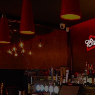 Bar iluminado com garrafas e letreiro Budweiser
