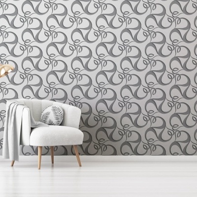 Cadeira branca com almofada e manta cinzentas diante de parede com padrão abstrato, junto a candeeiro de pé dourado