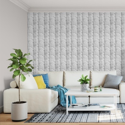 Sala com sofá branco, almofadas coloridas, mesa branca, planta, papel de parede geométrico cinzento.