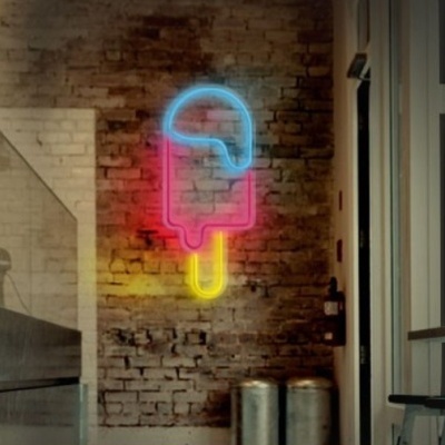 Letreiro néon de gelado partido na parede de tijolo num café