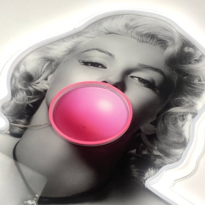 Mulher loira a soprar bola de chiclete rosa sobre fundo branco