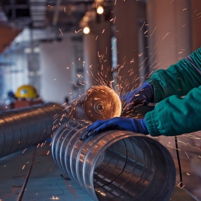 Trabalho com ferramenta elétrica de corte num tubo metálico numa oficina