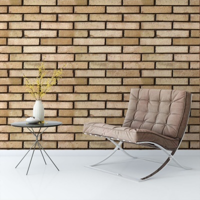 Cadeira lounge castanha com mesa de apoio cinza e parede de tijolos claros