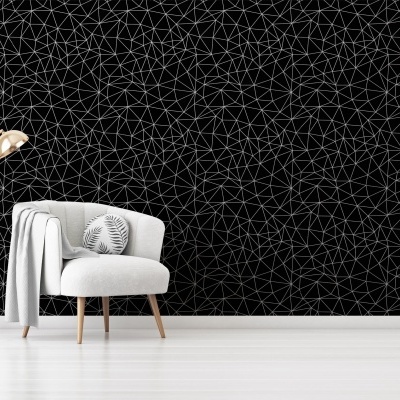 Parede com papel de parede preto com padrão geométrico branco, cadeira branca e candeeiro dourado