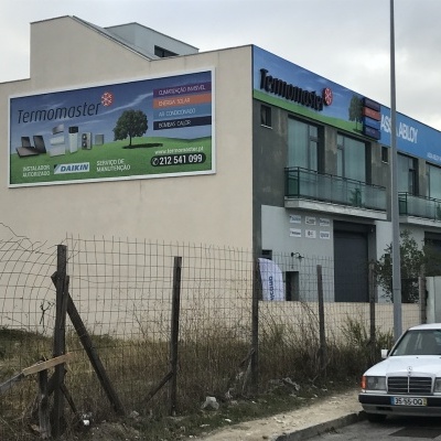 Prédio comercial com painéis Termomaster e um carro branco estacionado em frente