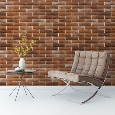 cadeira moderna estofada cinza com mesa lateral preta e vaso de flores amarelas num ambiente com parede de tijolos marrons