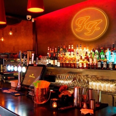 Bar moderno com iluminação vermelha, garrafas e copos no balcão