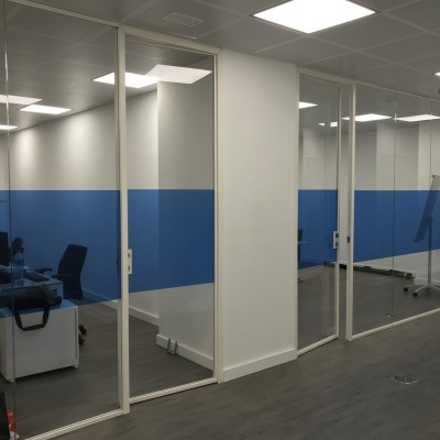 Divisórias de vidro com painéis azuis em escritório moderno com piso de madeira