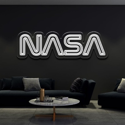 Sala escura com letreiro luminoso NASA, sofá preto, poltrona preta, mesas de centro brancas e planta em vaso branco.