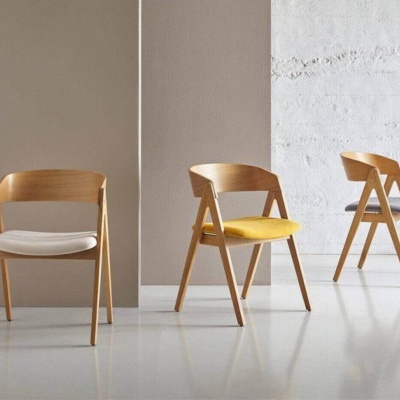 Três cadeiras de madeira com almofadas coloridas numa sala minimalista