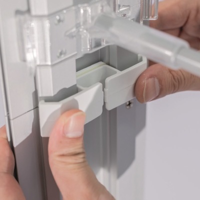 Mãos ajustando peça branca e cinzenta de plástico com encaixes móveis
