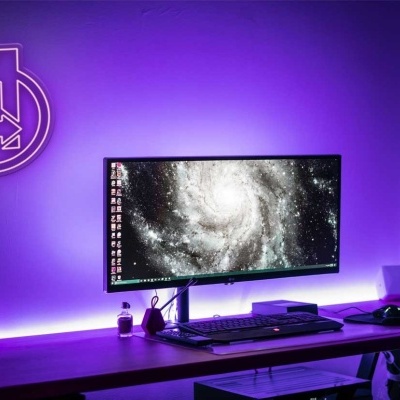 Setup de computador com monitor ultrapanorâmico e iluminação LED roxa
