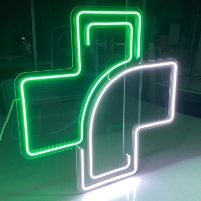 Sinal de néon em forma de cruz farmacêutica verde e branca em ambiente interior