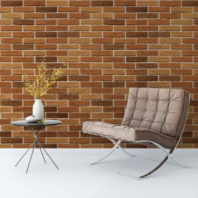 Cadeira castanha com mesa lateral preta e vaso branco com flores amarelas frente a parede de tijolos