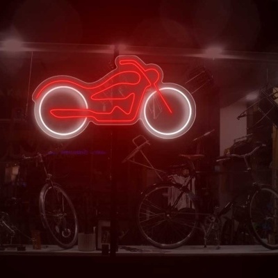 Montra escura com bicicletas e luz neon vermelha em forma de motocicleta