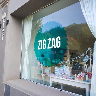 Vitrine de loja com adesivo verde 'ZIG ZAG' e produtos variados no interior