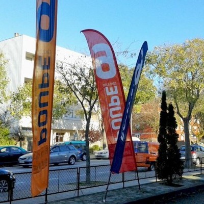 Três bandeiras publicitárias verticais coloridas com texto 'BONDE' em passeio urbano