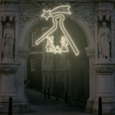 Arco arquitetónico em pedra com esculturas e iluminação decorativa numa rua urbana