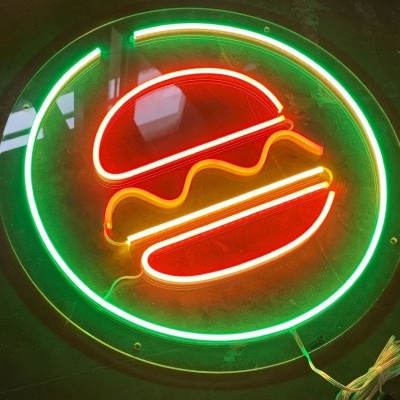 Sinal de néon com desenho de hambúrguer colorido numa parede escura