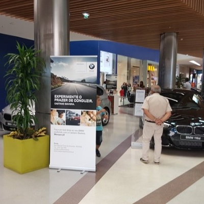 Carro BMW i3 preto em exposição num centro comercial ao lado de placa informativa em português