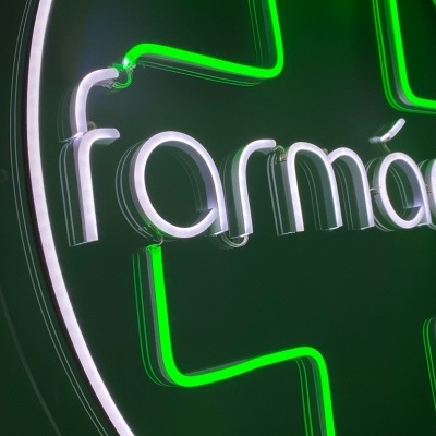 Sinal luminoso de farmácia com cruz verde e texto branco