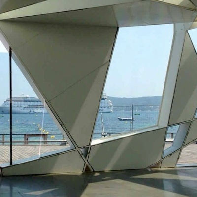 Barco de cruzeiro visto através de estrutura triangular branca com terraço de madeira