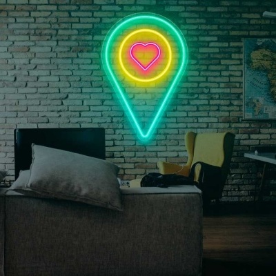 Lâmpada de neon de marcador com coração numa parede de tijolos cinza numa sala com sofá cinza e cadeira amarela