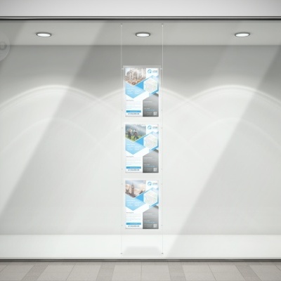 Vitrine de loja vazia com três cartazes verticais colados na parede branca.