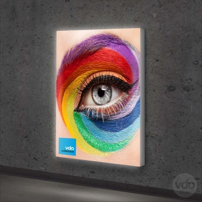 Painel com imagem de olho maquilhado em arco-íris pendurado em parede cinzenta